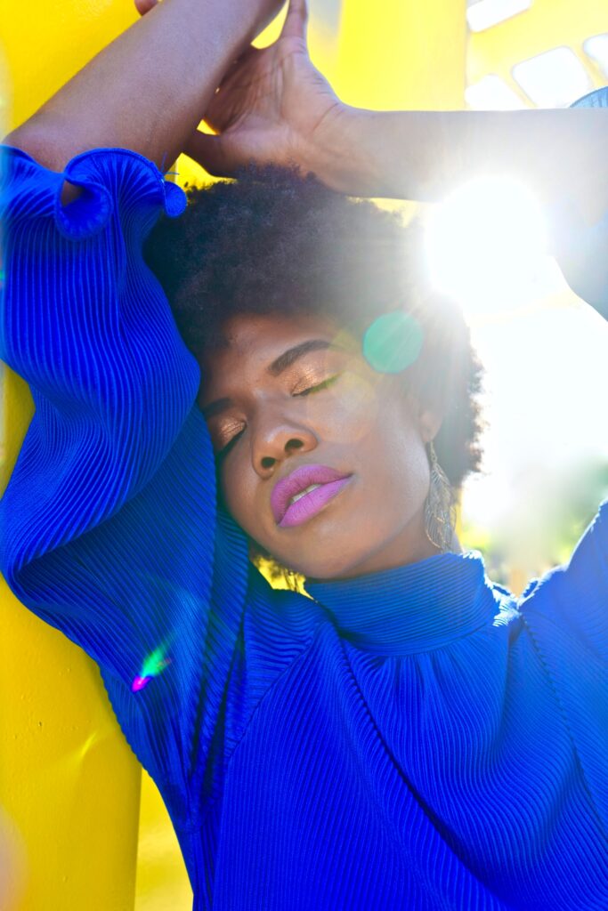 close up of a Black woman against the bright sun in a blue sweater. She seems free. Perhaps she got anxiety treatment in Cincinnati, Oh or online therapy for anxiety in Ohio or kentucky 