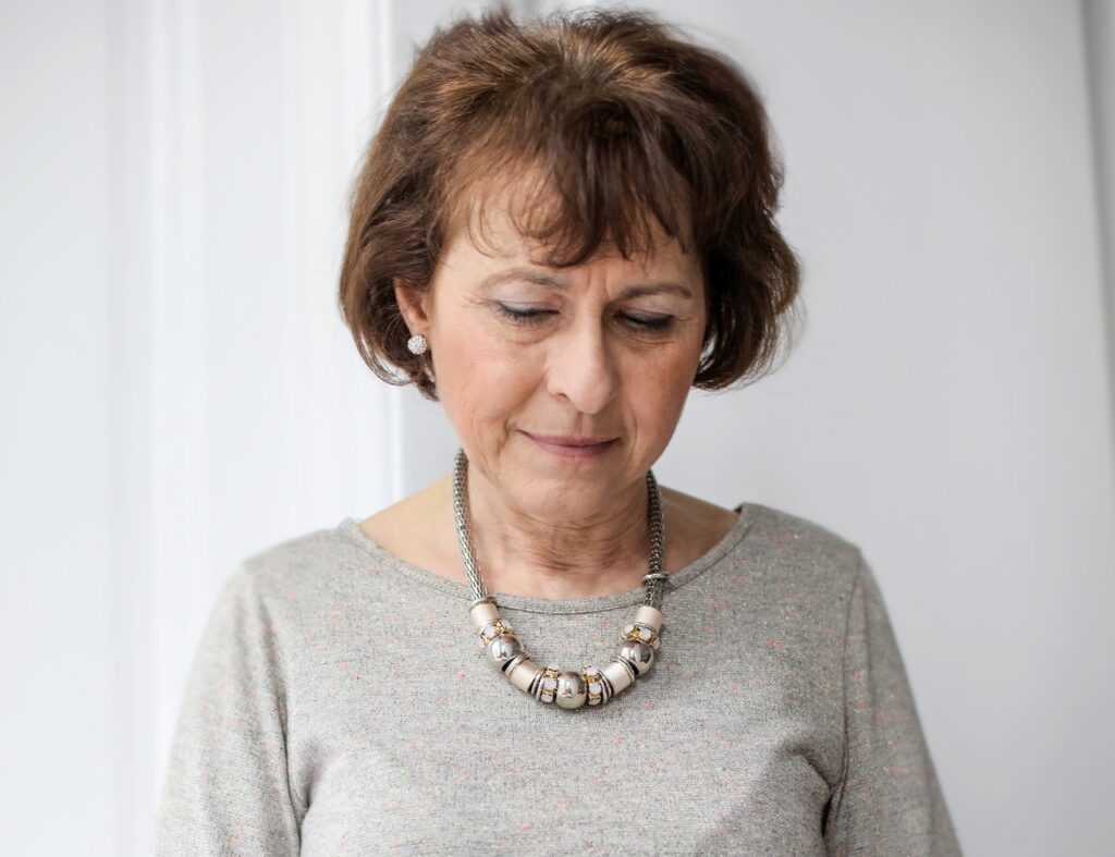An older woman looks towards the ground with an concerned expression. This represents the toll that sexual pain or vaginismus has on your a woman's confidence. Learn how to overcome painful intercourse in Cincinnati, OH by searching "painful intercourse treatment in Kentucky" or "painful intercourese treatment in Indiana." 