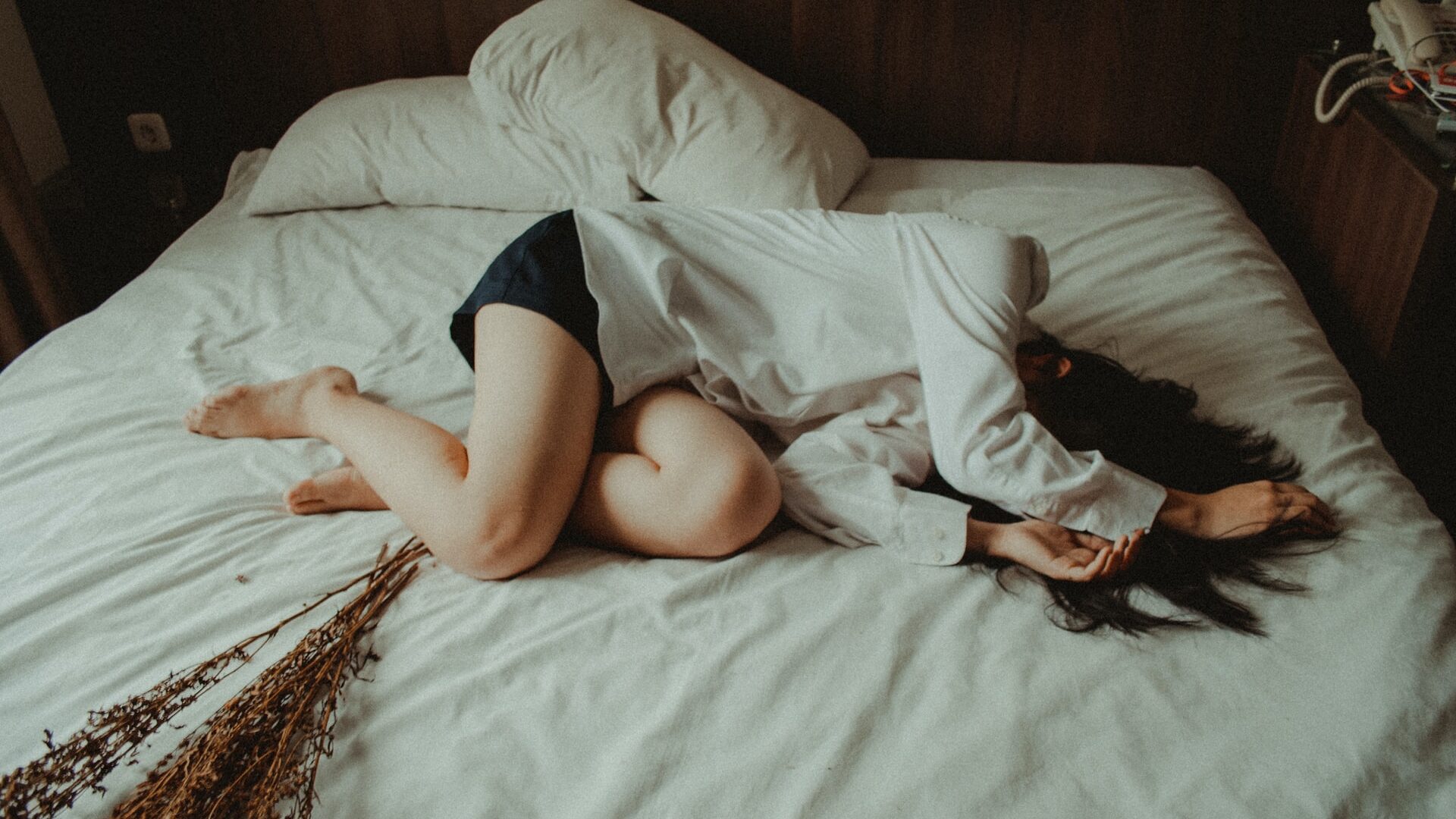 A woman lays in bed with her arms covering her face. She appears exhausted as she tries to work up the energy to get up. This could symbolize the fatigue felt from depression symptoms. We offer support with depression treatment in Cincinnati, OH, CBT for depression, and other services. Contact a depression therapist for support today!