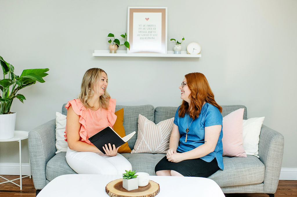 Two therapists with Emma Schmidt & Assoc. smile as they talk to one another. They offer therapy in Cincinnati, OH and a varitey of services including yoga therapy in Cincinnati, OH, relationship therapy in cincinnati, OH, and other services. 45208